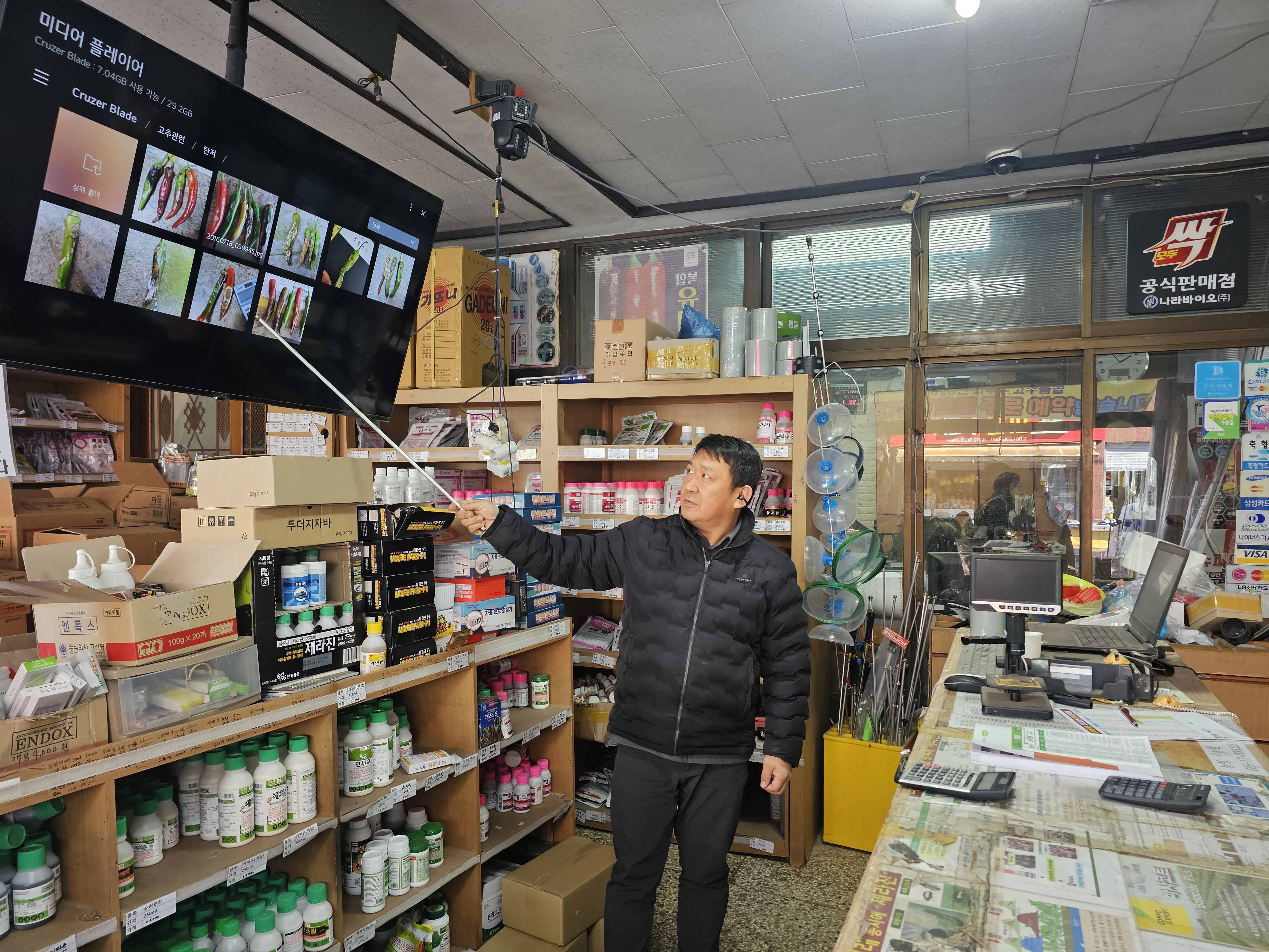부농원 대표가 매장에서 농약과 종자 상품을 직접 설명하며 농사 상담하는 모습